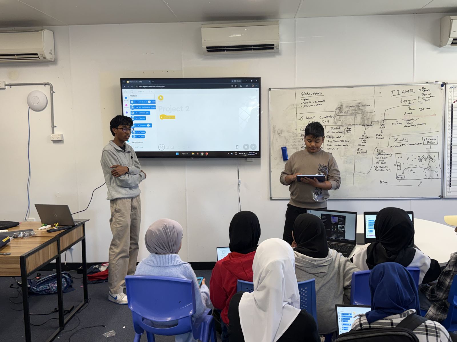 Two student mentors leading a coding lesson for a class