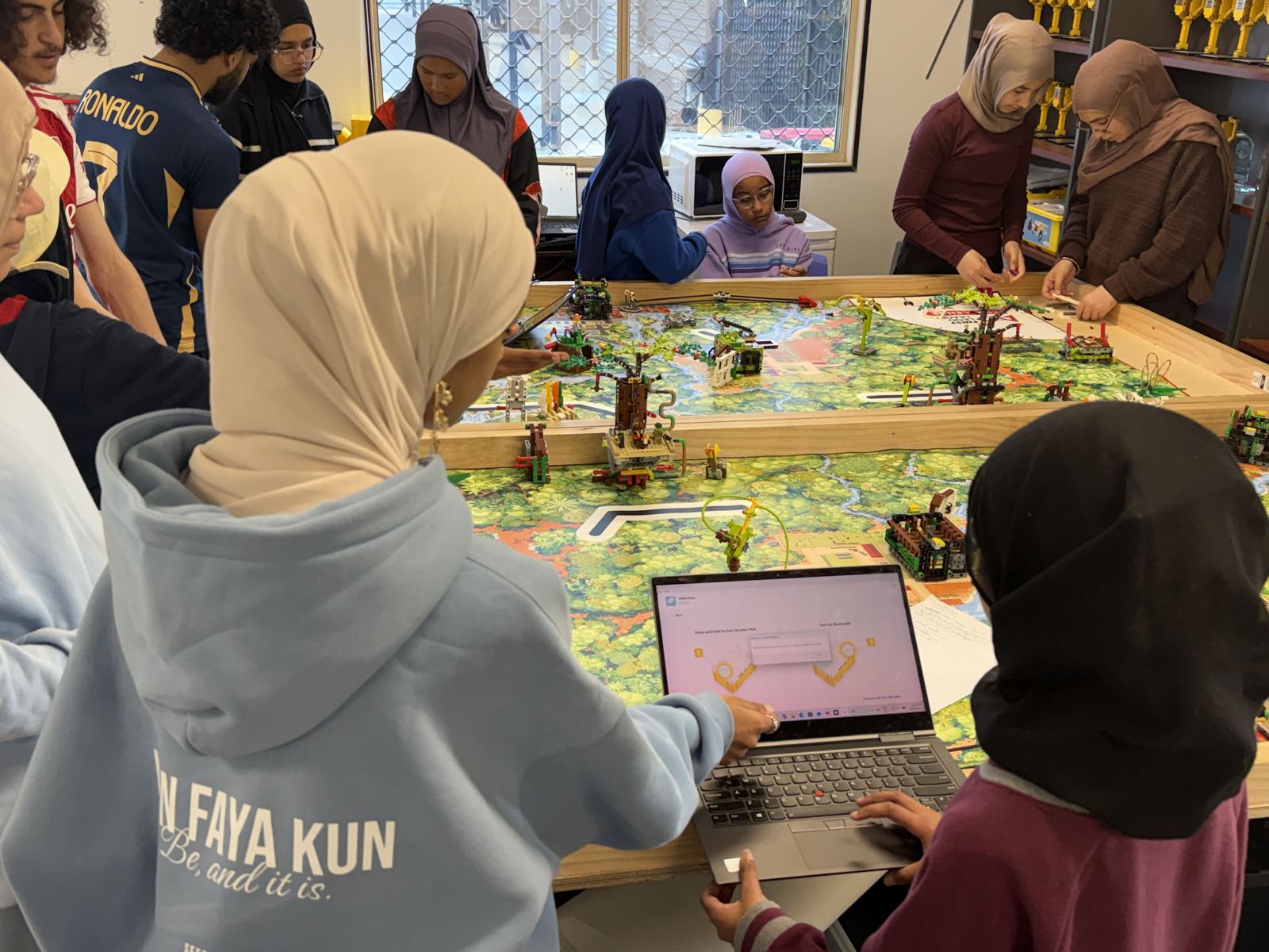 Students testing a robot on a game field with a laptop