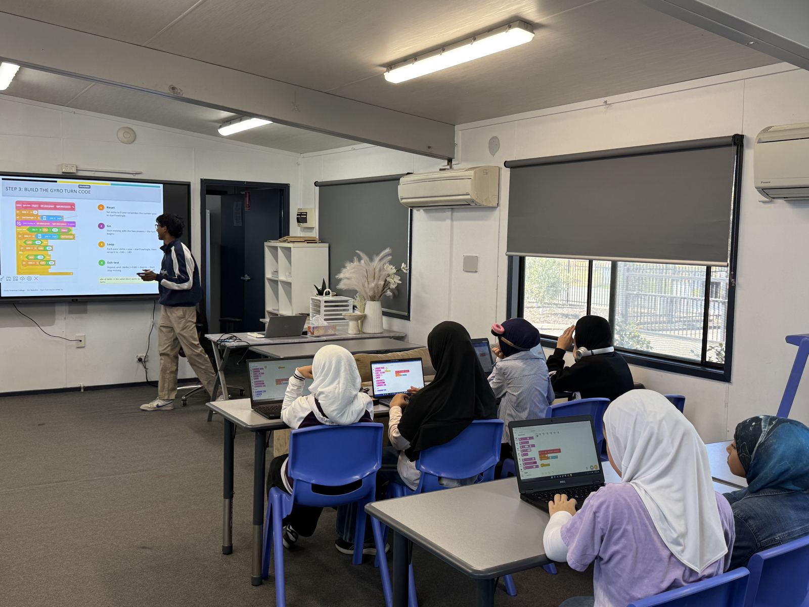 Students coding on laptops in a classroom workshop