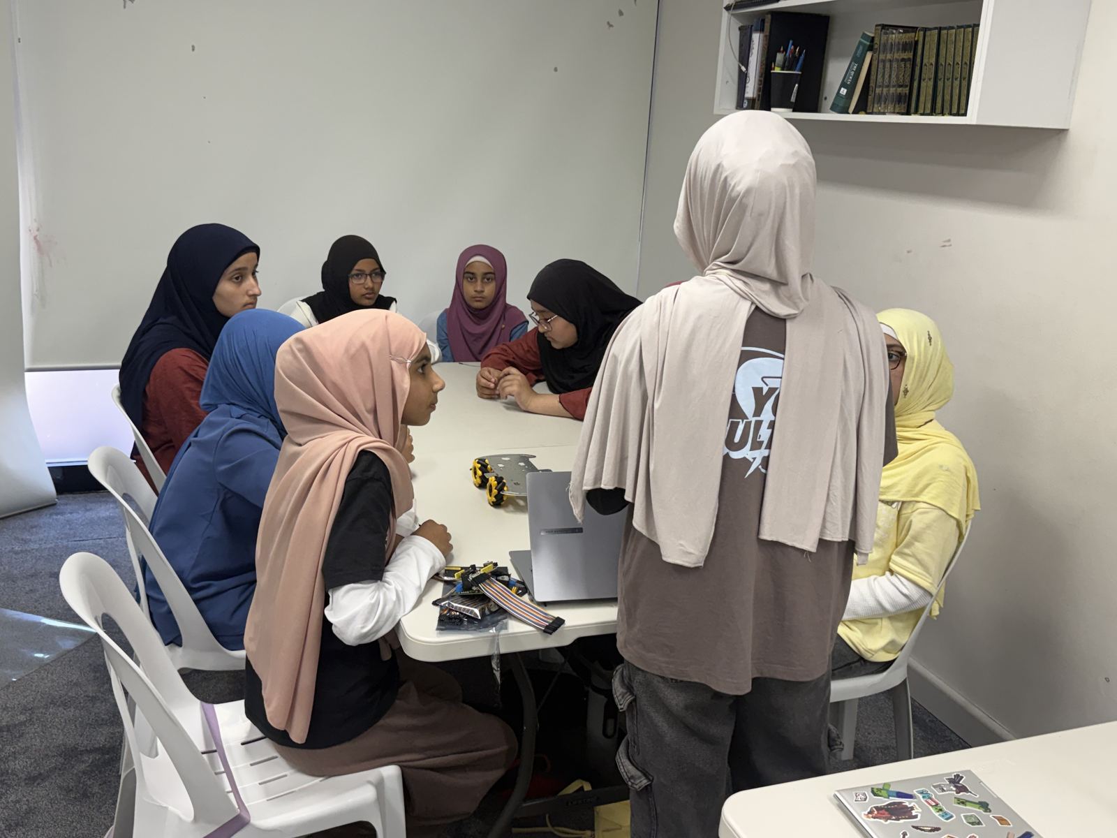 Students wiring a robot together while a mentor watches